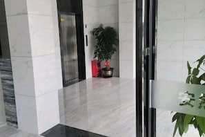 A lobby with a marble floor, a red cabinet, and a potted plant.