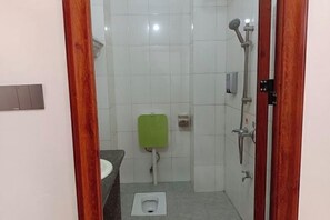 A small bathroom with a toilet, a green urinal, and a shower. - Anran Convenience Hotel Zhangzhou (Wuzhou)