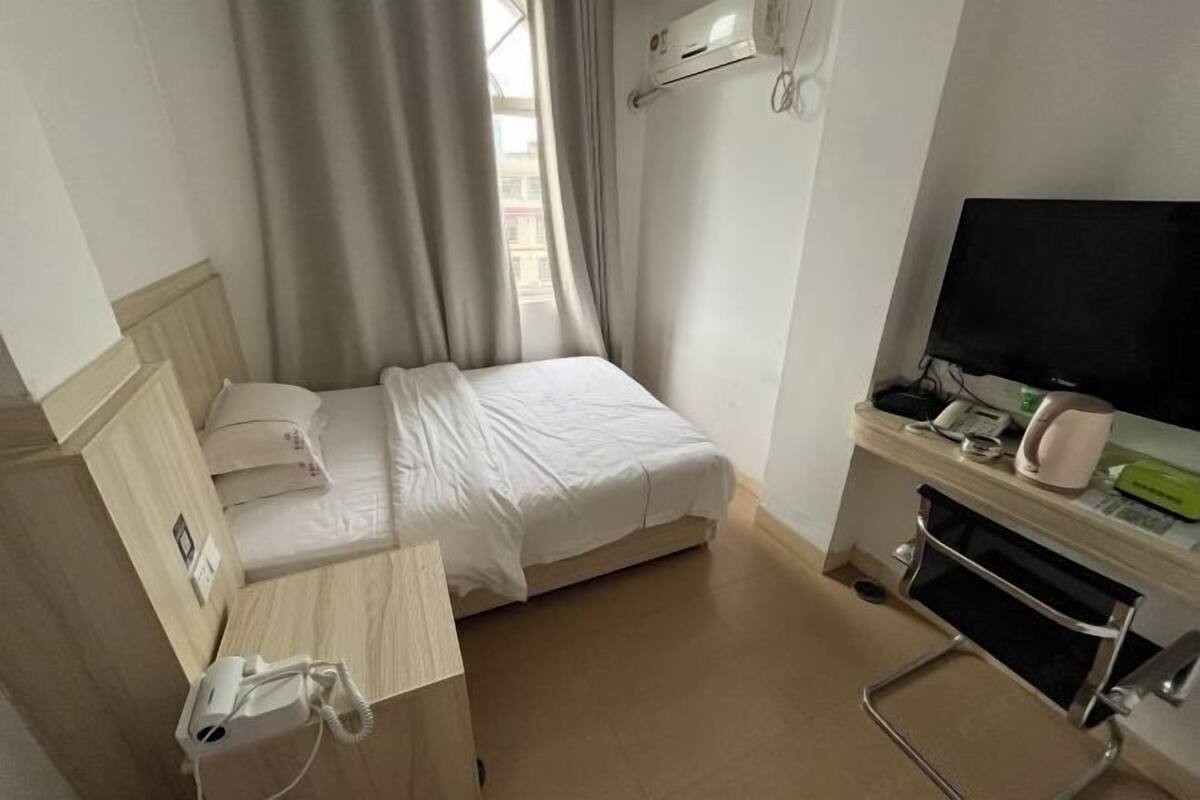 Une chambre d’hôtel équipée d’un lit, d’un bureau avec un téléphone, d’une télévision et d’un appareil de climatisation.