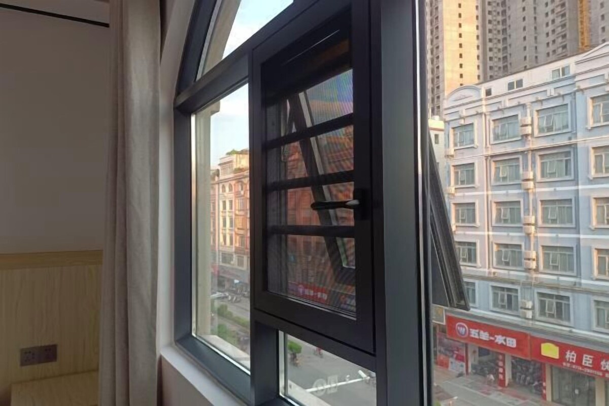 A window with a view of a cityscape, including buildings and a street.