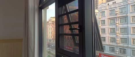 A window with a view of a cityscape, including buildings and a street.