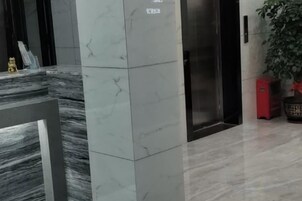 A reception area with a marble reception desk, a red storage unit, and a potted plant.
