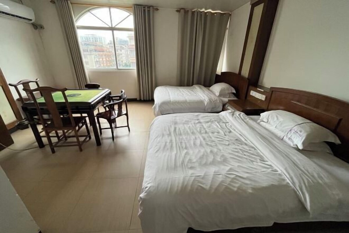 A hotel room with two beds, a table with chairs, and a window with curtains.
