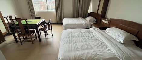 A hotel room with two beds, a table with chairs, and a window with curtains.