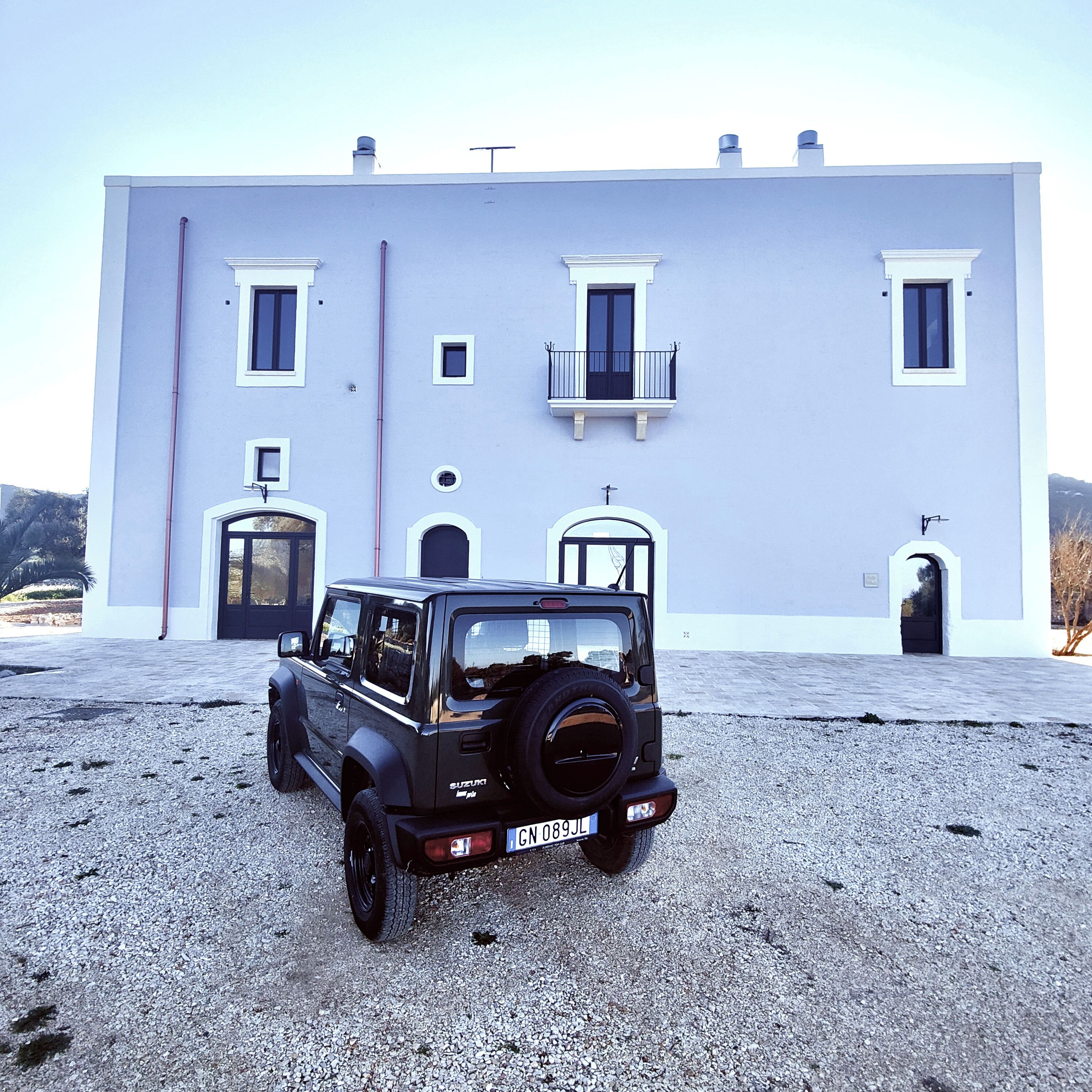 A black off-road vehicle parked in front of a large, light-colored building with multiple windows and doors.