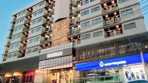 Een hotel met meerdere verdiepingen, balkons, een autoverhuurservice en een blauwe gevel.