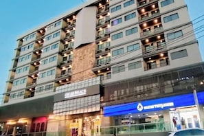 A multi-story hotel with a modern facade, featuring a prominent 'CARPLACE' sign and a 'COUNTRYTHRIFT' store. - Oscar Palace Hotel & Wellness Center (Sadao)