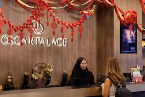 A reception desk with a sign reading 'OSCAR PALACE' and a woman standing behind it. - Oscar Palace Hotel & Wellness Center (Sadao)