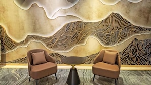 Una habitación moderna con un diseño de pared texturizado único, dos sillones de cuero y una mesa redonda negra.