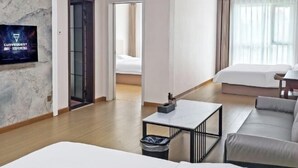 Una habitación de hotel moderna con pared de mármol, televisor de pantalla plana, sofá, cama y una pequeña mesa.