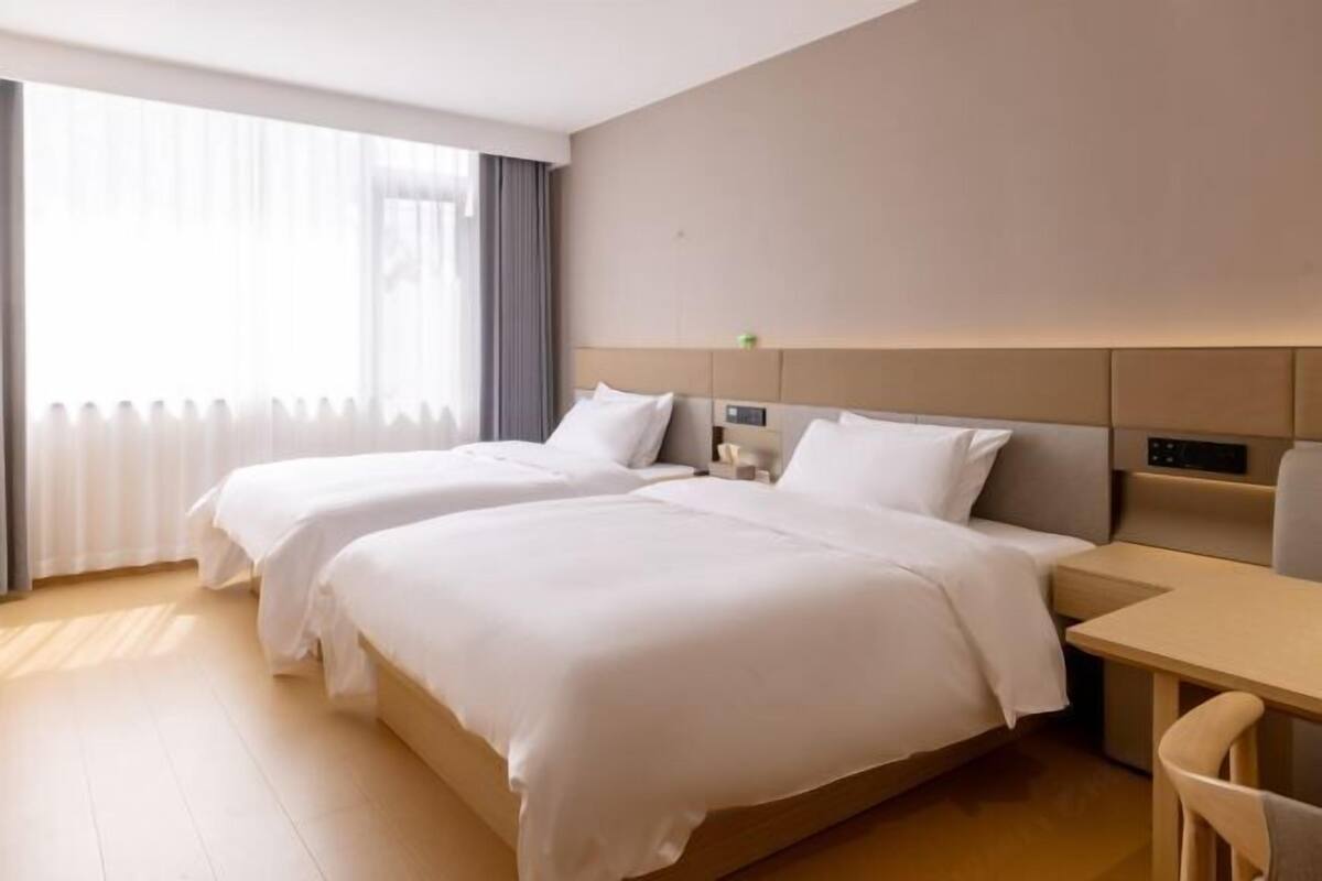 A hotel room with two beds, a desk, and a chair.