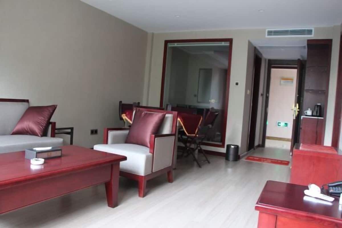 Habitación de hotel moderna con un sofá gris, una mesa de centro roja y un comedor con una silla y mesa.