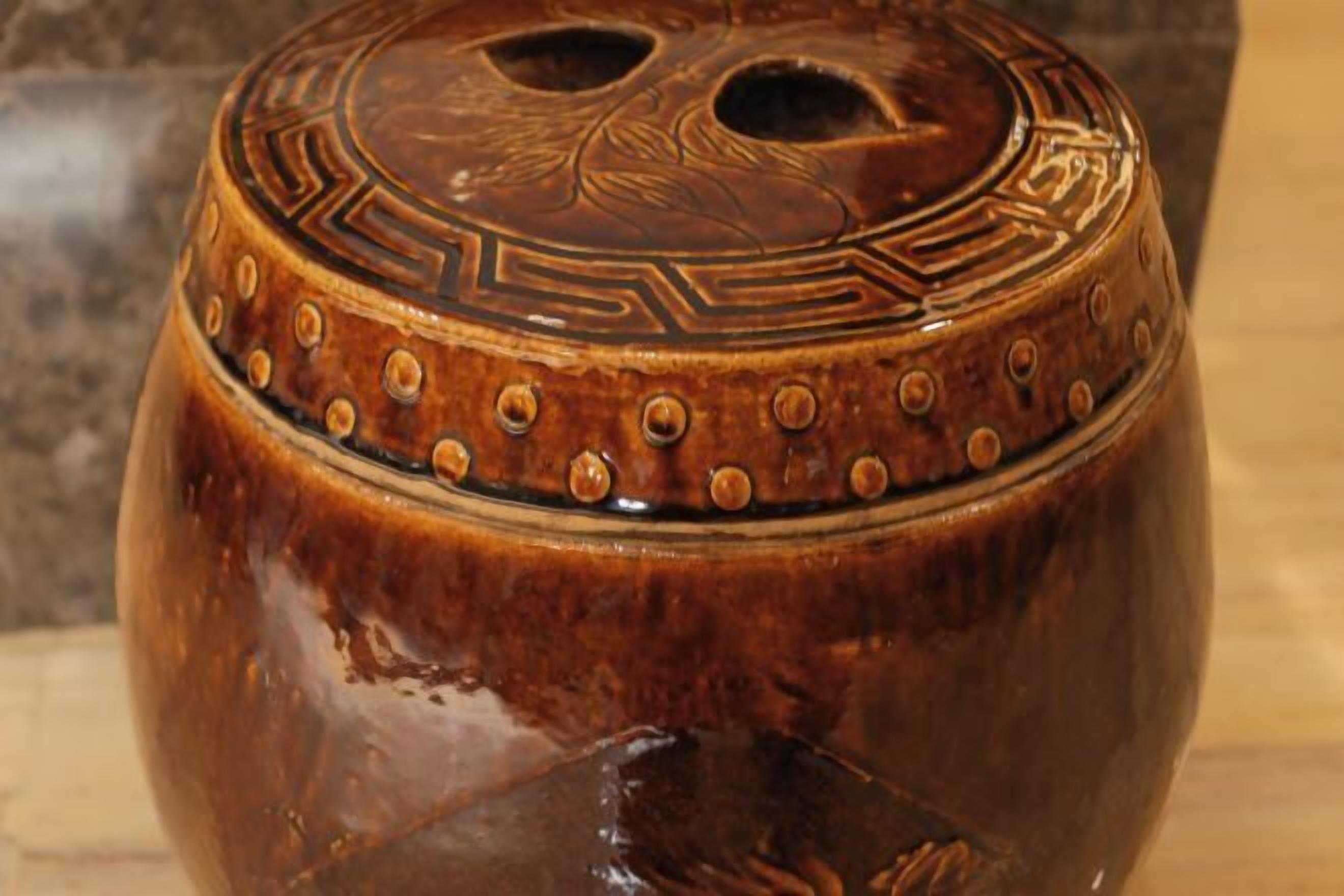 A close-up of a ceramic pot with a decorative lid featuring geometric patterns and circular motifs.