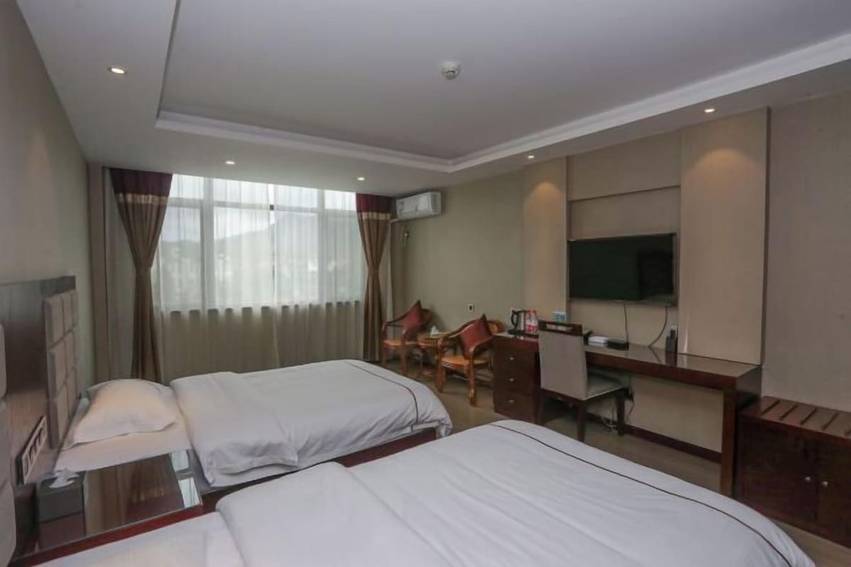 Une chambre d’hôtel avec deux lits, un bureau, une chaise, un téléviseur et un appareil de climatisation.