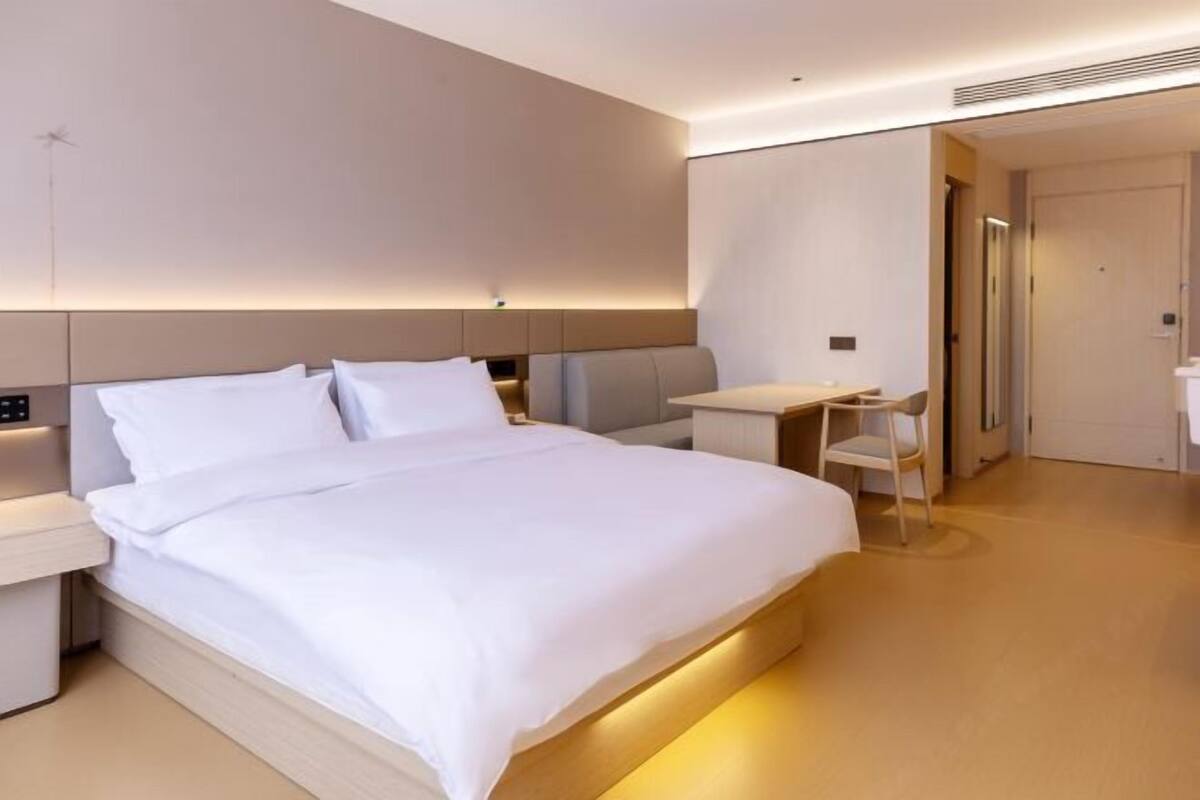 A modern hotel room with a large bed, bedside tables, a desk, and a chair.