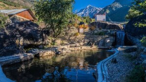 A natural pool with a stone pathway, surrounded by trees and a mountain backdrop. - Hill Ventures (Dharamshala)