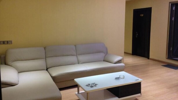 A living room with a beige sofa and a small coffee table. - Tanghe Inn, Yucheng (Rucheng)