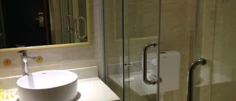 A bathroom with a round white sink, a mirror, and a glass shower enclosure.