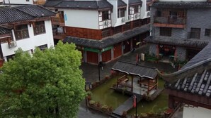 A traditional courtyard with a small pavilion, surrounded by multi-story buildings with tiled roofs and wooden balconies.