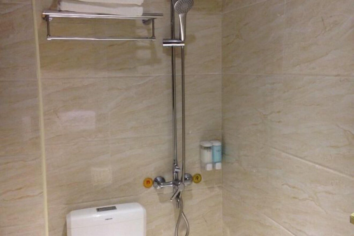 A bathroom with a shower, a towel rack, and a toilet.