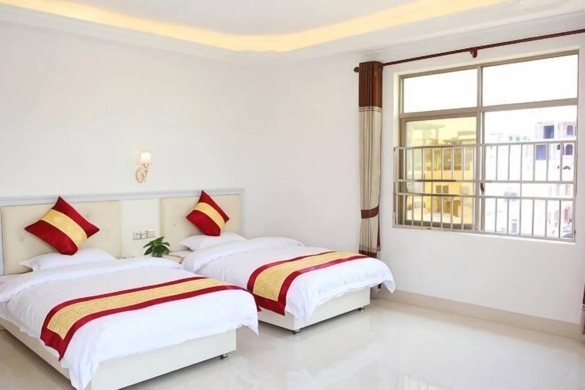 A hotel room with two beds, a window with a view, and a nightstand with a lamp.