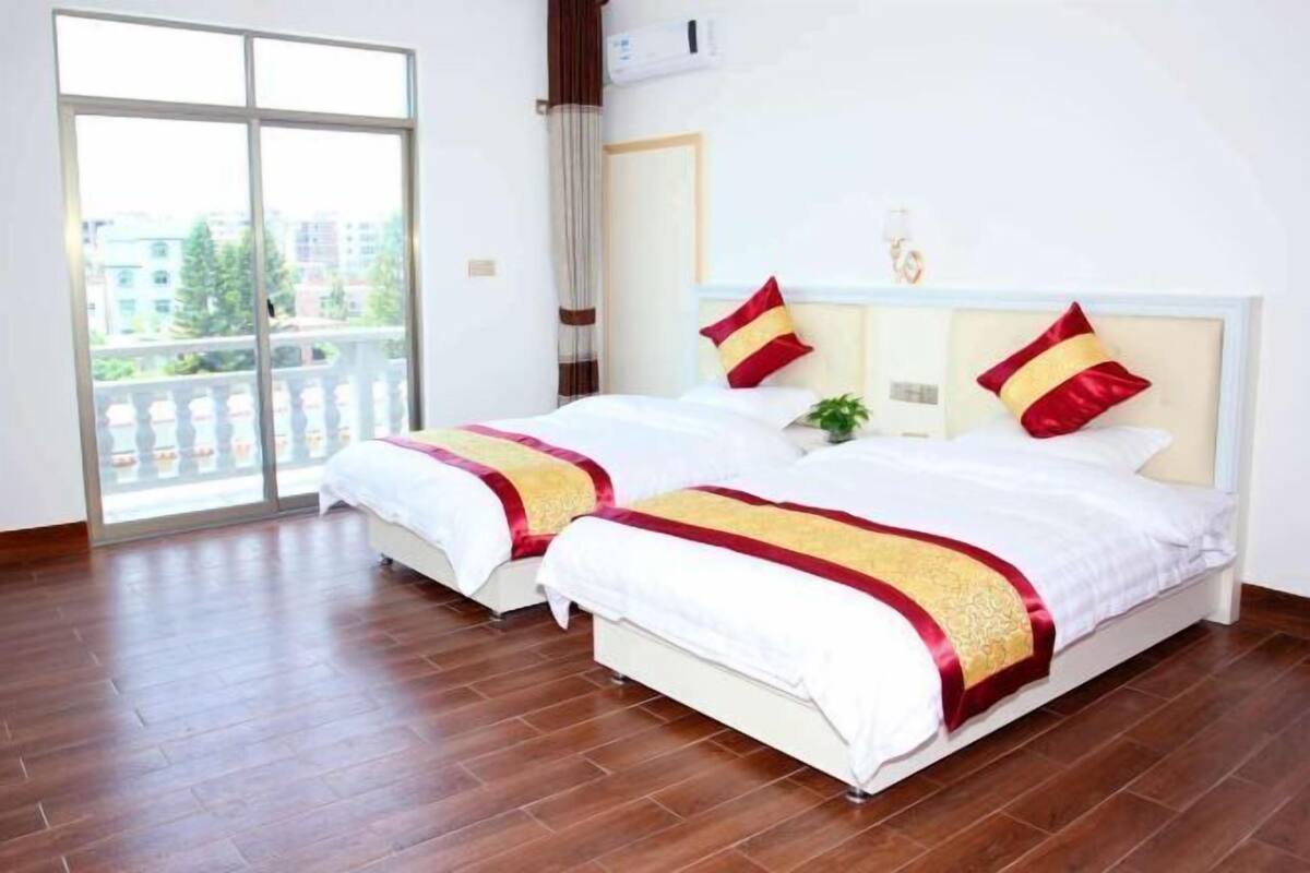 A hotel room with two beds, a balcony, and a view of buildings.