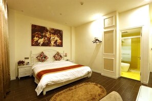 Une chambre à coucher avec un lit, une table de chevet, un tableau, une armoire et une salle de bain.