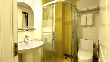 A bathroom with a glass shower enclosure, a sink, and a toilet.