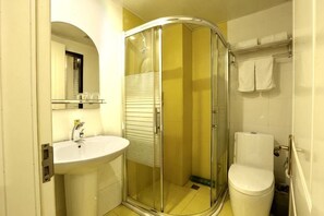 Une salle de bain avec une douche à parois de verre, un lavabo et des toilettes.