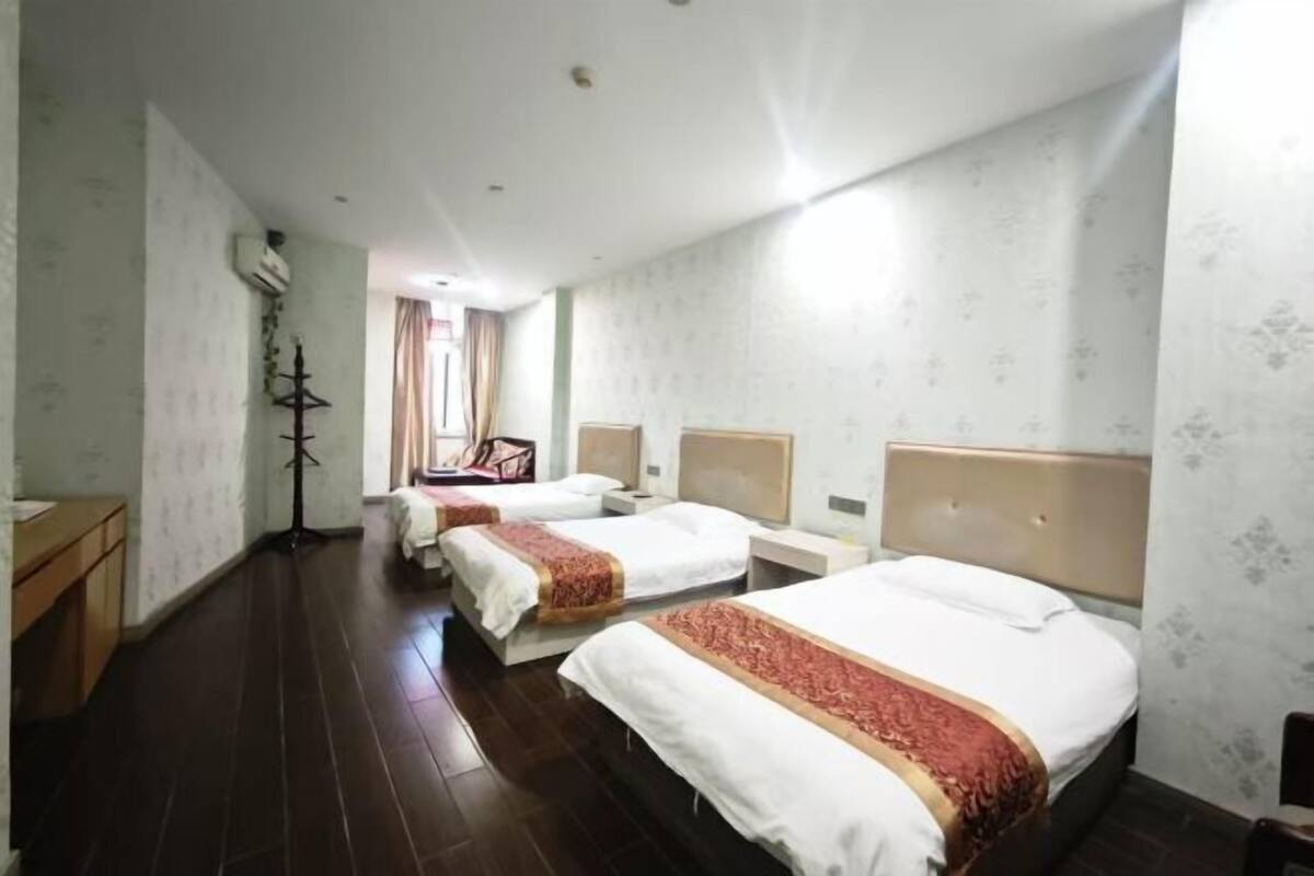 A hotel room with two beds, a wooden dresser, a desk, and a chair.
