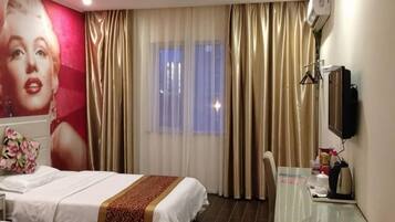 A hotel room with two beds, a desk, a chair, a television, and a large window with curtains.