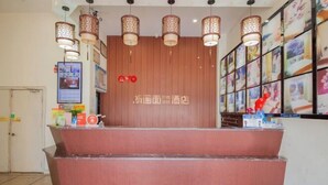 Zona de recepción de un hotel con un mostrador de madera, múltiples lámparas colgantes e imágenes enmarcadas en las paredes.
