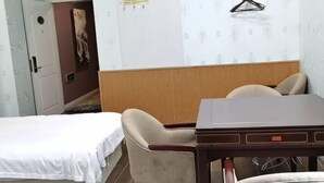 Una habitación de hotel con una cama, cabecera de madera, una mesa y dos sillas.