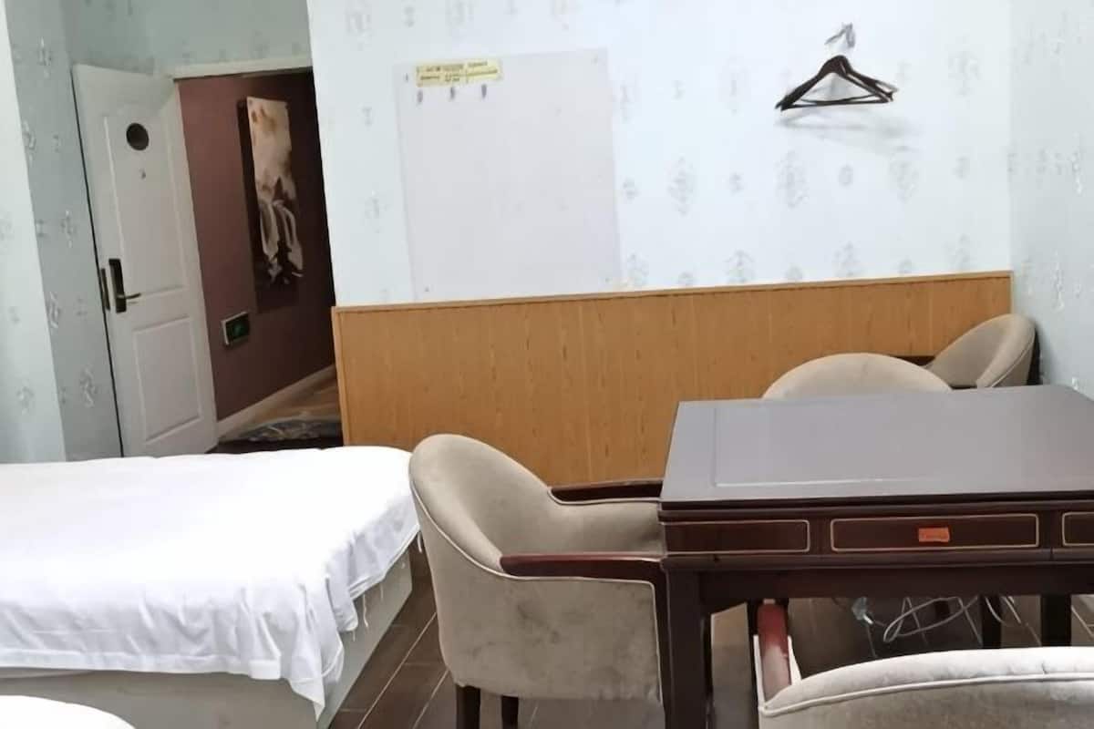 A hotel room with a bed, a wooden headboard, a table, and two chairs.