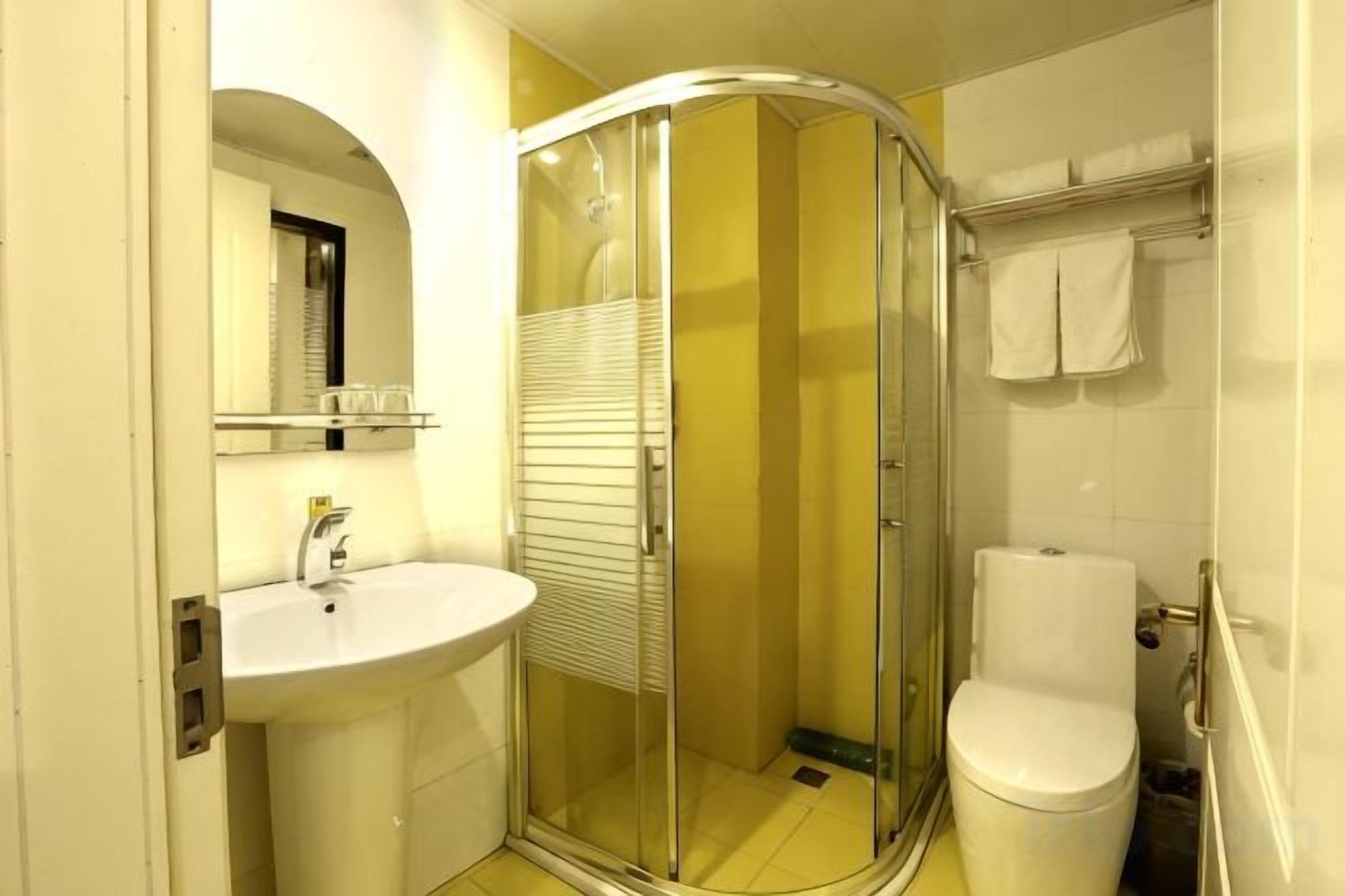 A bathroom with a glass shower enclosure, a white sink, and a toilet.