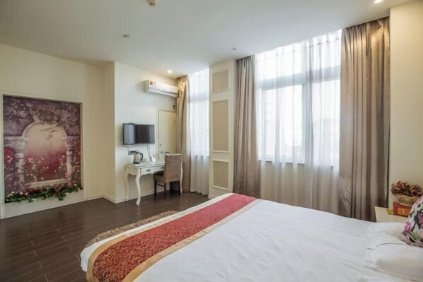Habitación de hotel con una cama grande, un escritorio con silla, televisor y ventana con cortinas.