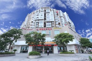 A multi-story building with a commercial ground floor, large windows, and a clear sky. - Xinhuamian Fashion Hotel (Wenzhou)