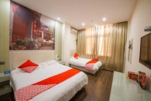 Ein Hotelzimmer mit zwei Betten, einem Fernseher, einem Schreibtisch und einem großen Fenster mit Vorhängen.