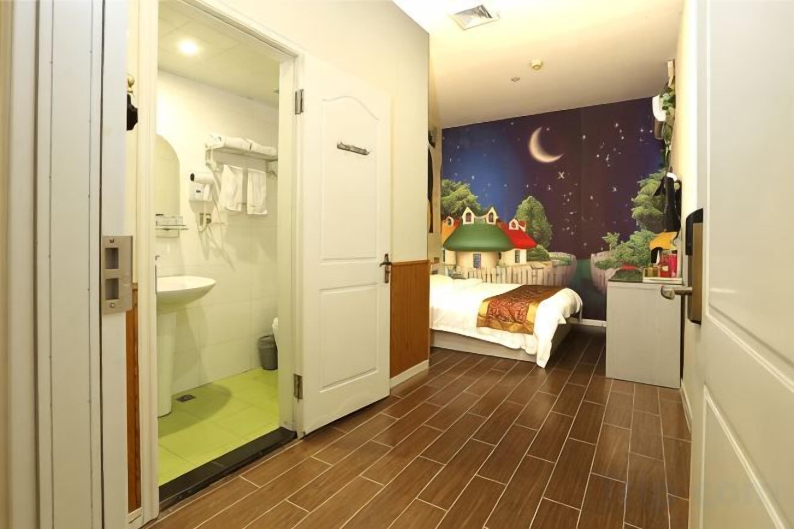 A bedroom with a bed, a night sky mural, a small desk, and a nightstand.