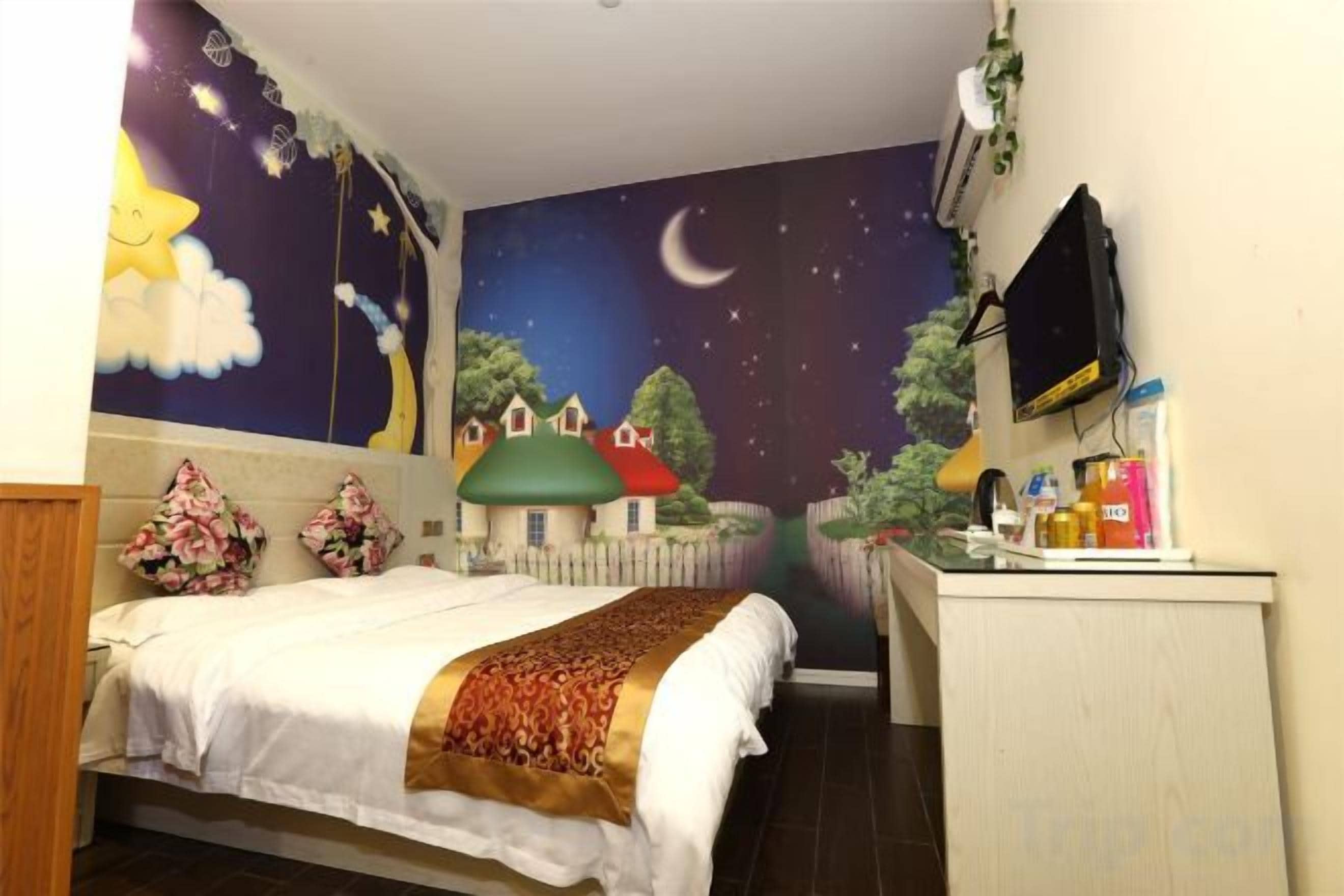 A bedroom with a bed, a desk, and a night sky mural on the wall.