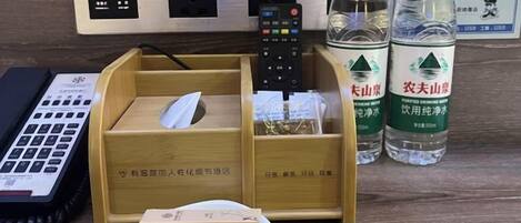 A desk with a keyboard, a remote control, a tissue box, and two water bottles.