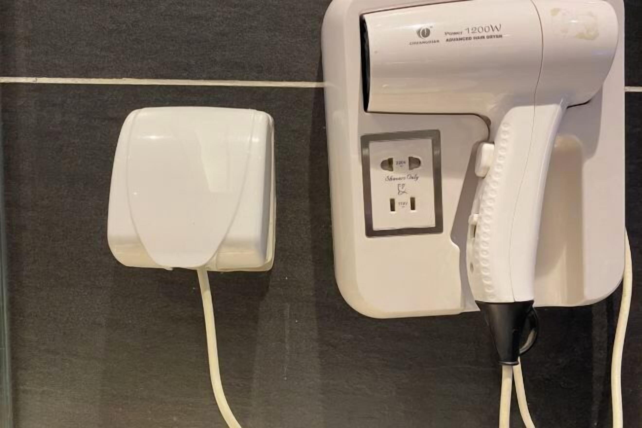 A hair dryer and a phone charger mounted on a wall.