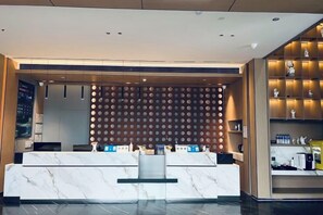 A hotel reception area with a marble counter, a wall of circular decorations, and a shelf with various items. - Yiwang Hotel Collection (Wenzhou Avenue) (Wenzhou)