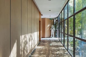 Un couloir doté d’un plancher en bois, de grandes fenêtres et d’une statue.