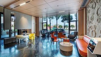 Un vestíbulo moderno con zonas de estar, ventanas amplias y vistas al exterior.