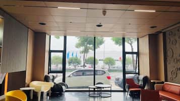Un hall de hotel con zona de estar, ventanas amplias y vistas a la calle.