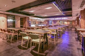 A restaurant with multiple tables and chairs, a kitchen area, and a modern ceiling design. - Yiwang Hotel Collection (Wenzhou Avenue) (Wenzhou)
