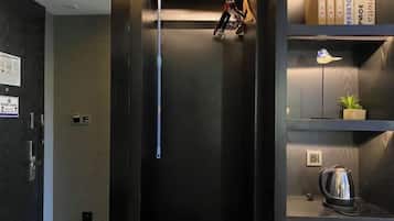 Un ascensor de hotel con interior oscuro, una pequeña planta en maceta y una tetera a la derecha.