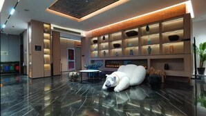 A modern lobby with a reflective floor, a polar bear sculpture, and a wall with shelves displaying decorative items. - Yiwang Hotel Collection (Wenzhou Avenue) (Wenzhou)