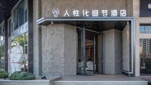 A hotel entrance with a modern design, featuring a textured facade and a clear sign above the entrance. - Yiwang Hotel Collection (Wenzhou Avenue) (Wenzhou)